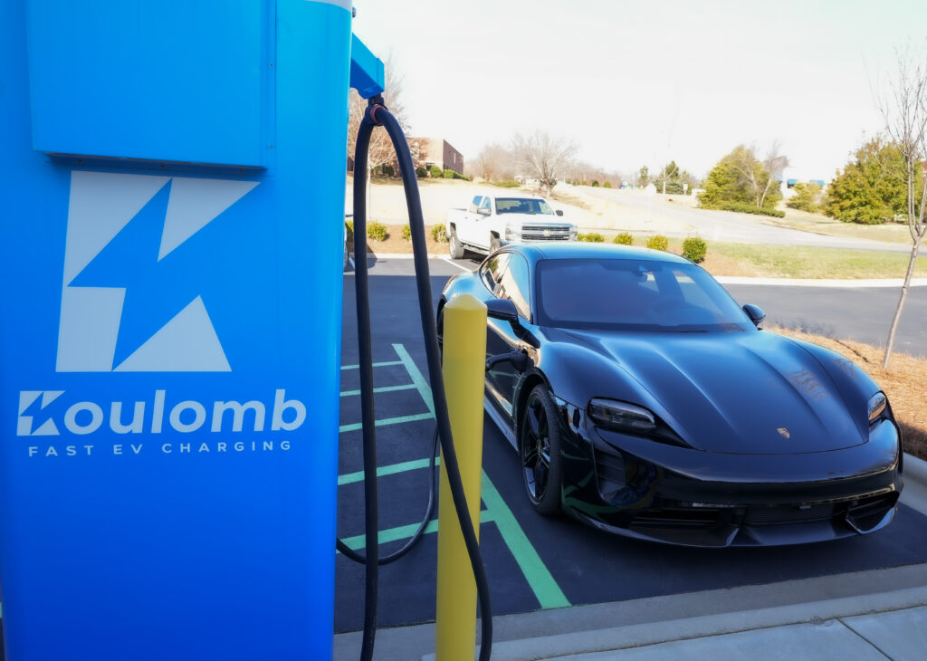 a black car parked next to a Koulomb electric vehicle charger